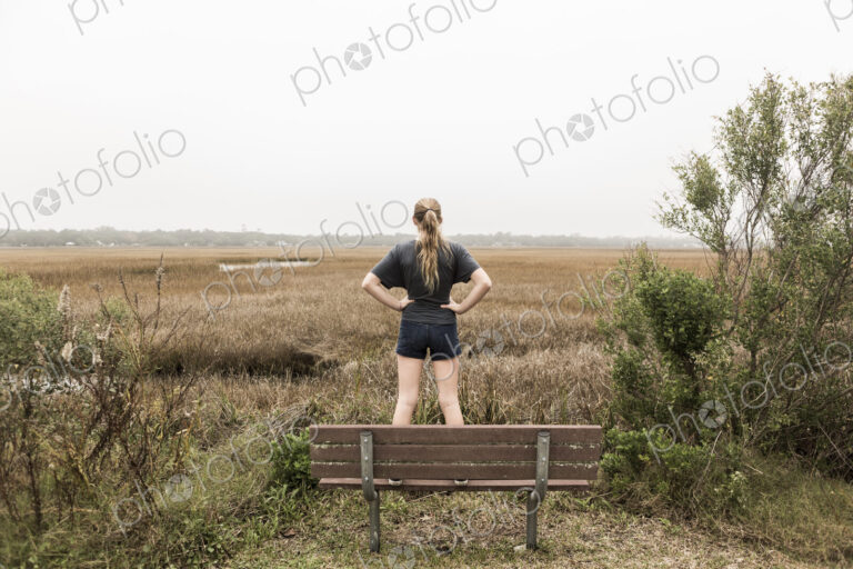 Teenage girl standing on a bench looking out over marshes, St. Simon's Island, Georgia