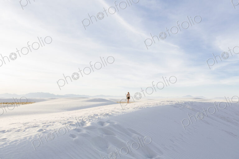 Teenage girl walking in white sand dunes, in open space.