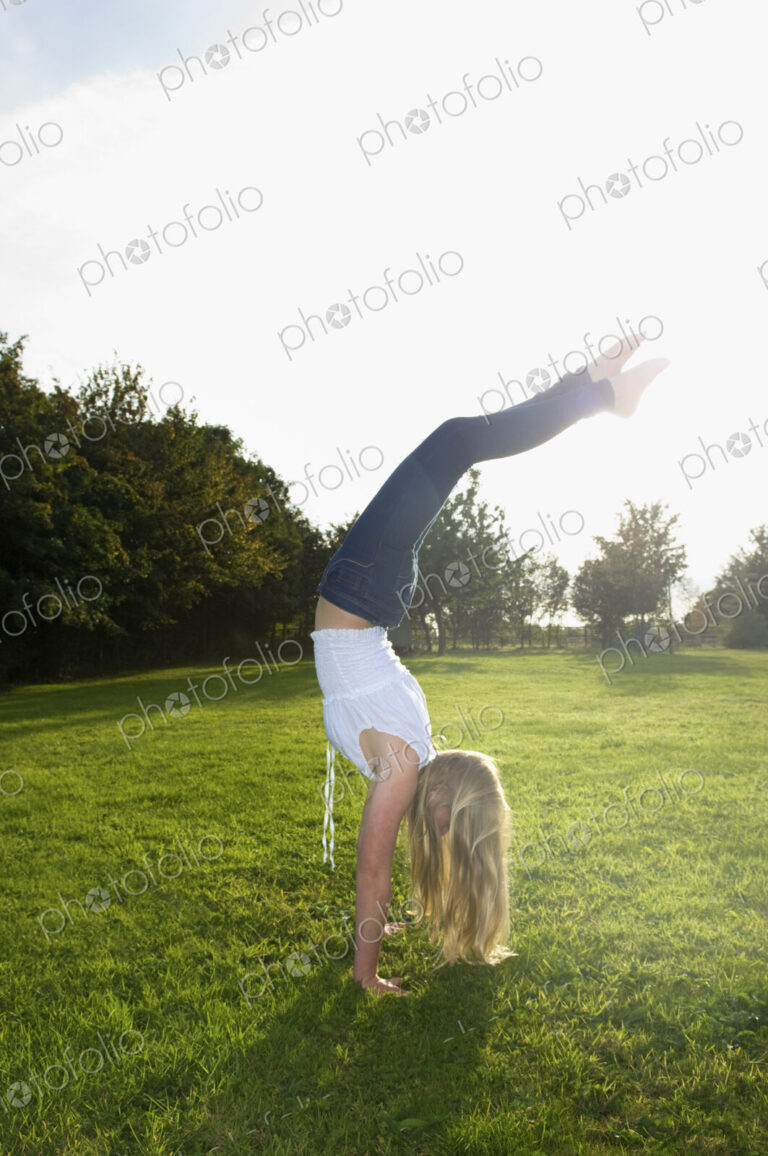 Teenage girl with long blond hair doing a headstand.