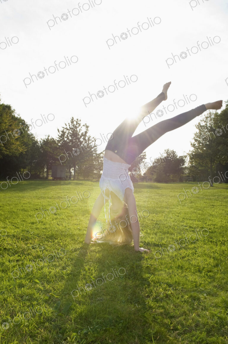 Teenage girl with long blond hair doing a headstand.
