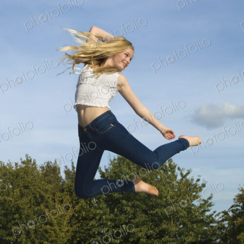 Teenage girl with long blond hair jumping in the air. Teenage girl with long blond hair jumping in the air.