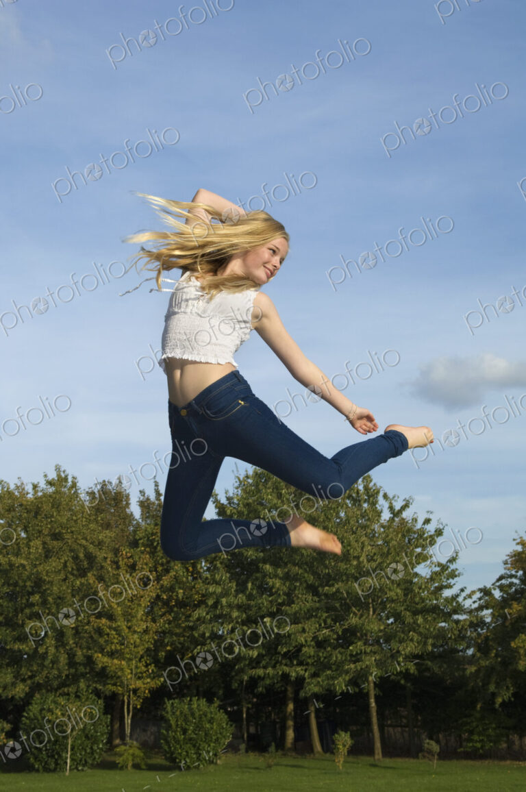 Teenage girl with long blond hair jumping in the air.