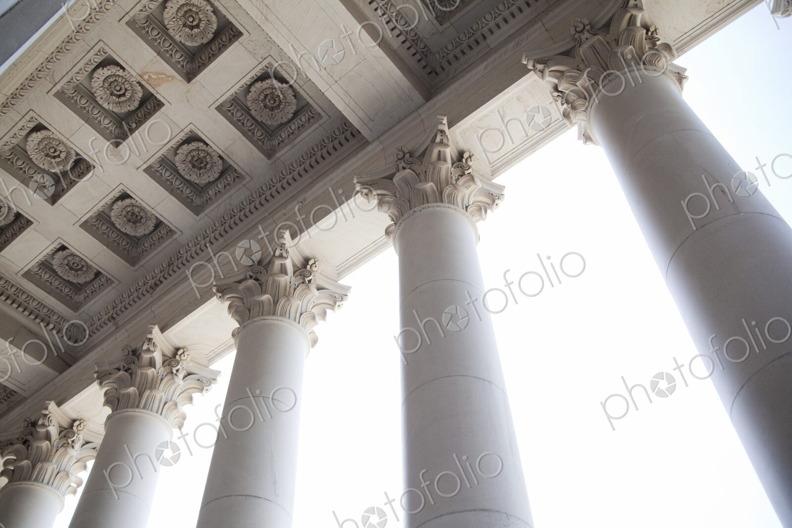 The American Capitol Building, a low angle view of the tall columns with gilded carved…