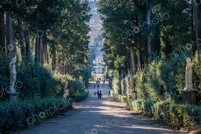 The Boboli Gardens in Florence, a tree lined path with statues and view of the central…