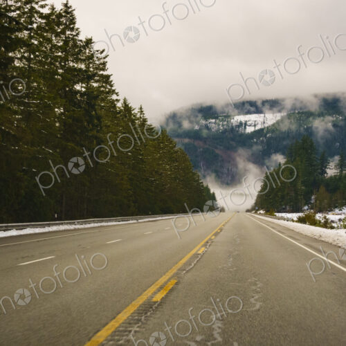 The Driver's view through the windshield of a winding road through the mountains in…