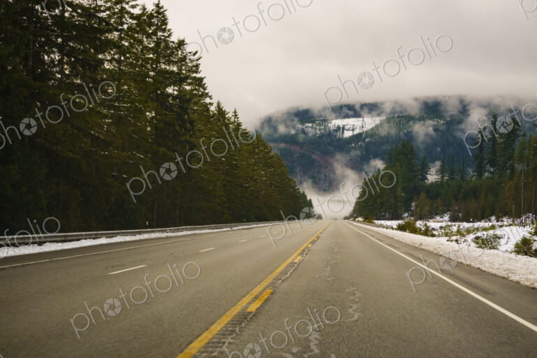 The Driver's view through the windshield of a winding road through the mountains in…