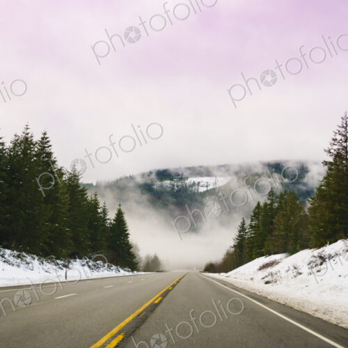 The Driver's view through the windshield of a winding road through the mountains in…