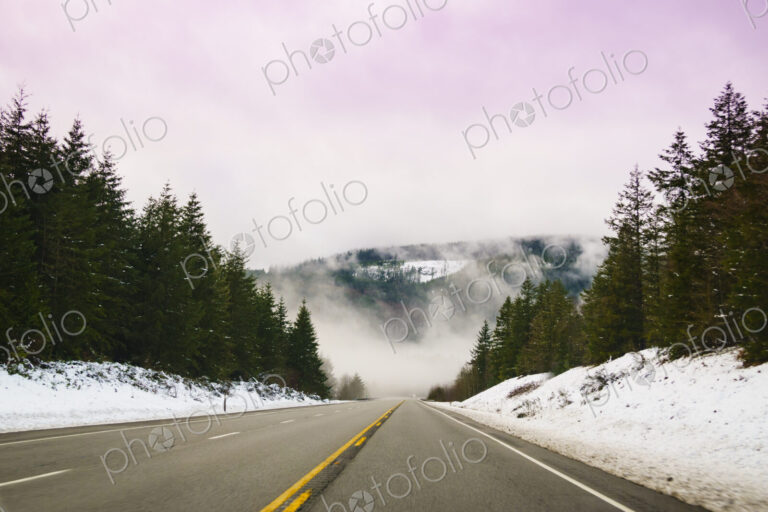 The Driver's view through the windshield of a winding road through the mountains in…