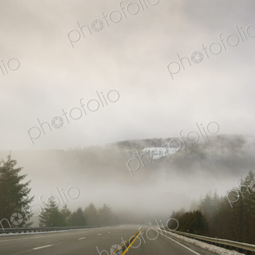The Driver's view through the windshield of a winding road through the mountains in…