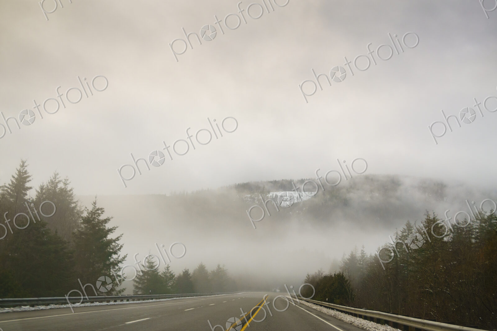 The Driver’s view through the windshield of a winding road through the mountains in…