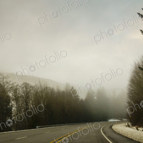 The Driver's view through the windshield of a winding road through the mountains in…