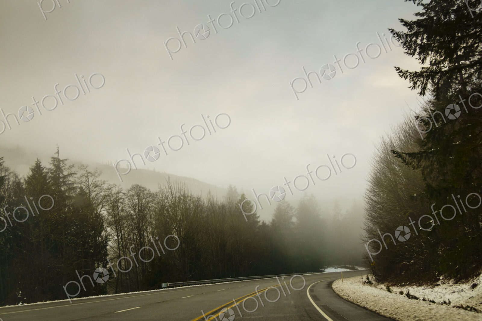 The Driver’s view through the windshield of a winding road through the mountains in…