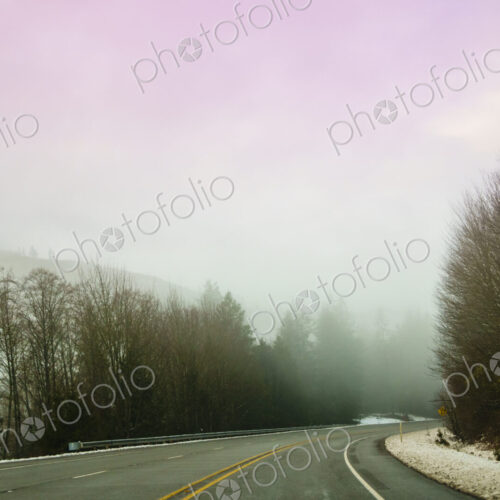 The Driver's view through the windshield of a winding road through the mountains in…