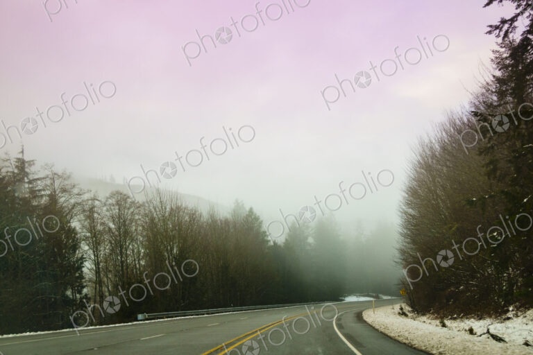 The Driver's view through the windshield of a winding road through the mountains in…