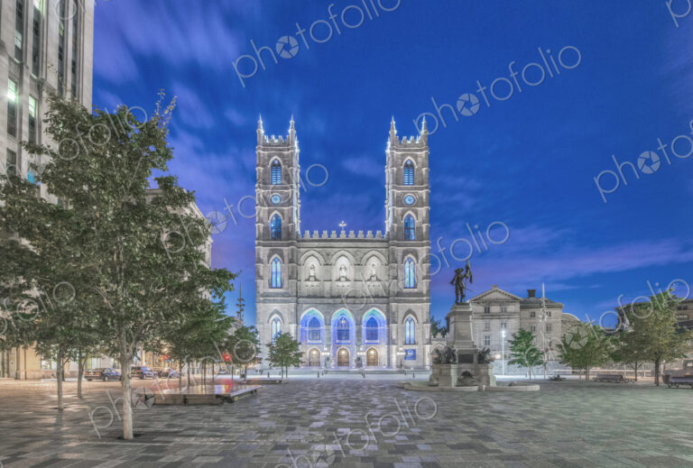 The Notre Dame Basilica, lit up at dusk in the city square in the Old Town of Montreal.