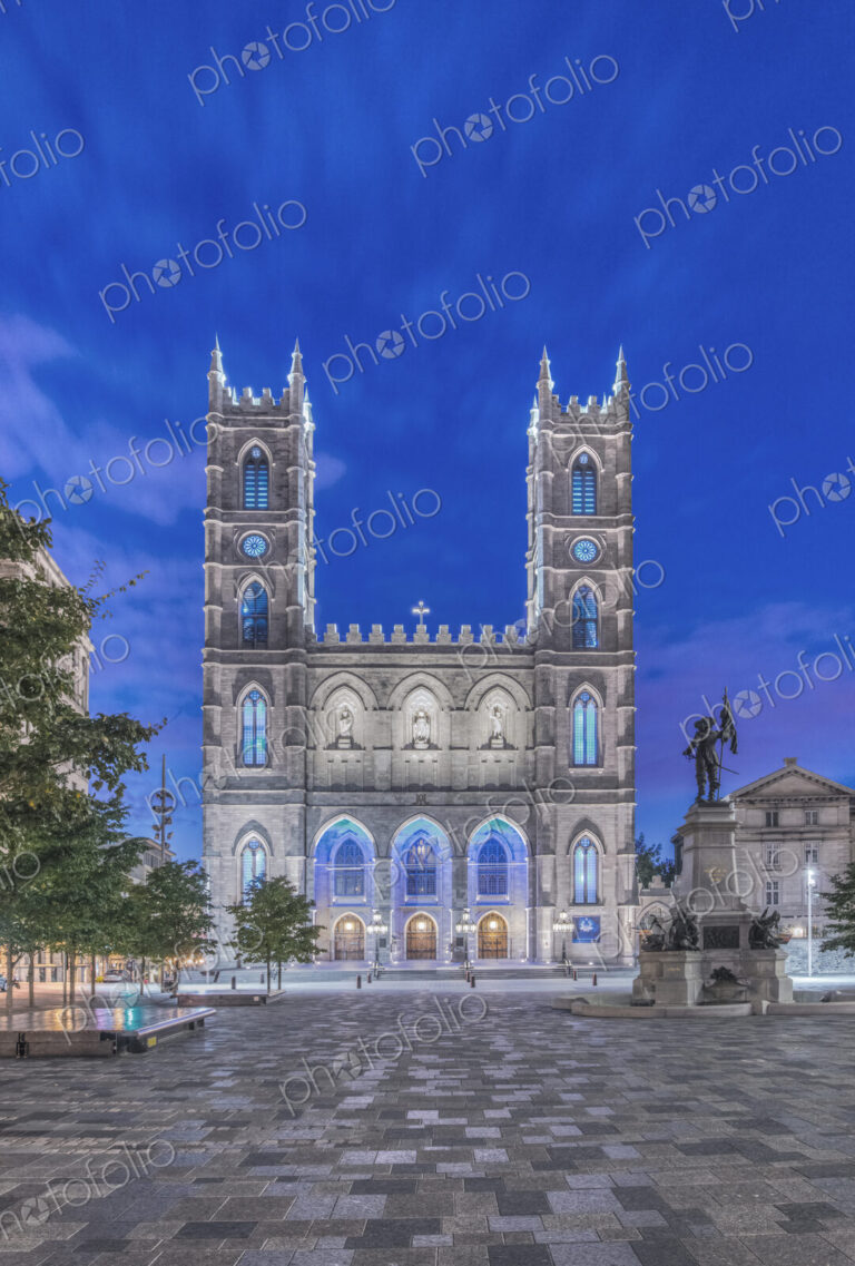 The Notre Dame Basilica, lit up at dusk in the city square in the Old Town of Montreal.