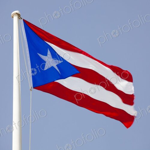 The Puerto Rican flag flutters boldly in the wind against a clear blue sky. Captured… The Puerto Rican flag flutters boldly in the wind against a clear blue sky. Captured…