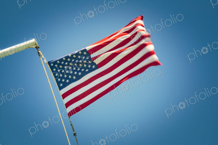 The United States flag flying against a blue sky, the stars and stripes.