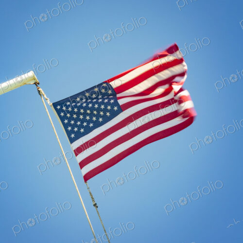 The United States flag flying against a blue sky, the stars and stripes.