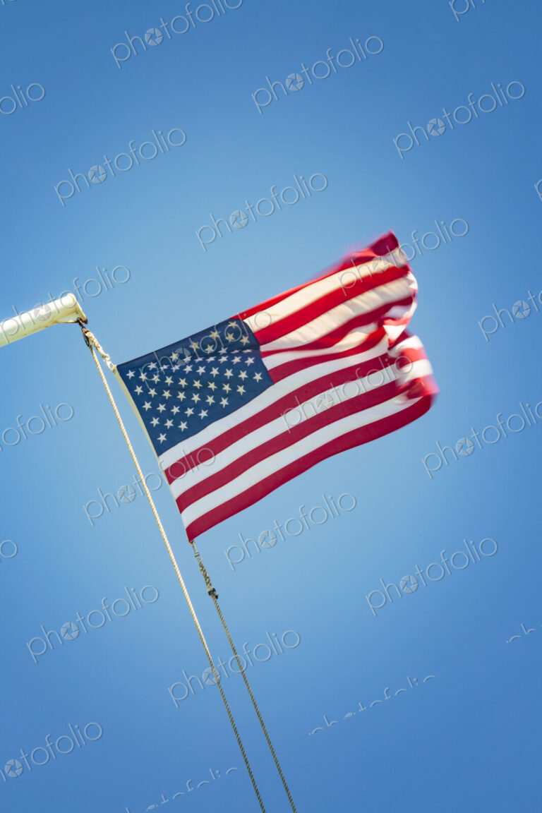 The United States flag flying against a blue sky, the stars and stripes.