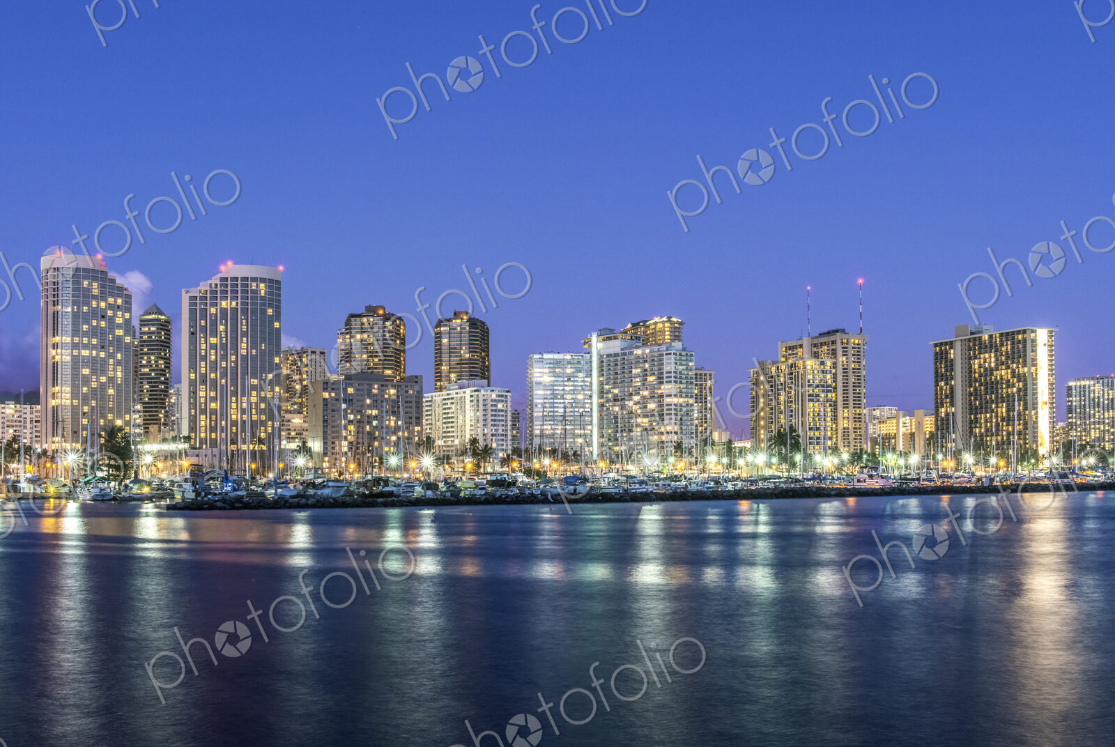 The Waikiki Skyline at dusk, tall buildings, downtown area, waterfront with moorings.