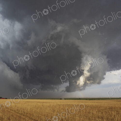 The back side of a Tornado-Warned Supercell, clouds on the horizon over farmland.