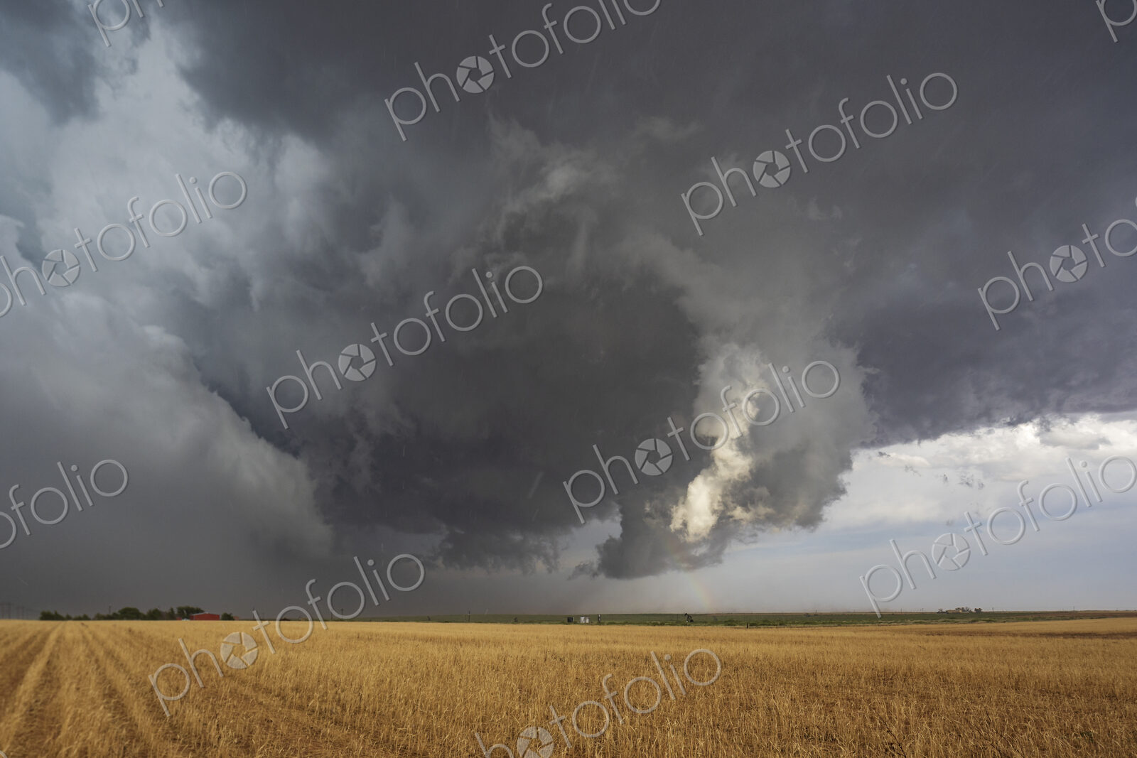The back side of a Tornado-Warned Supercell, clouds on the horizon over farmland.