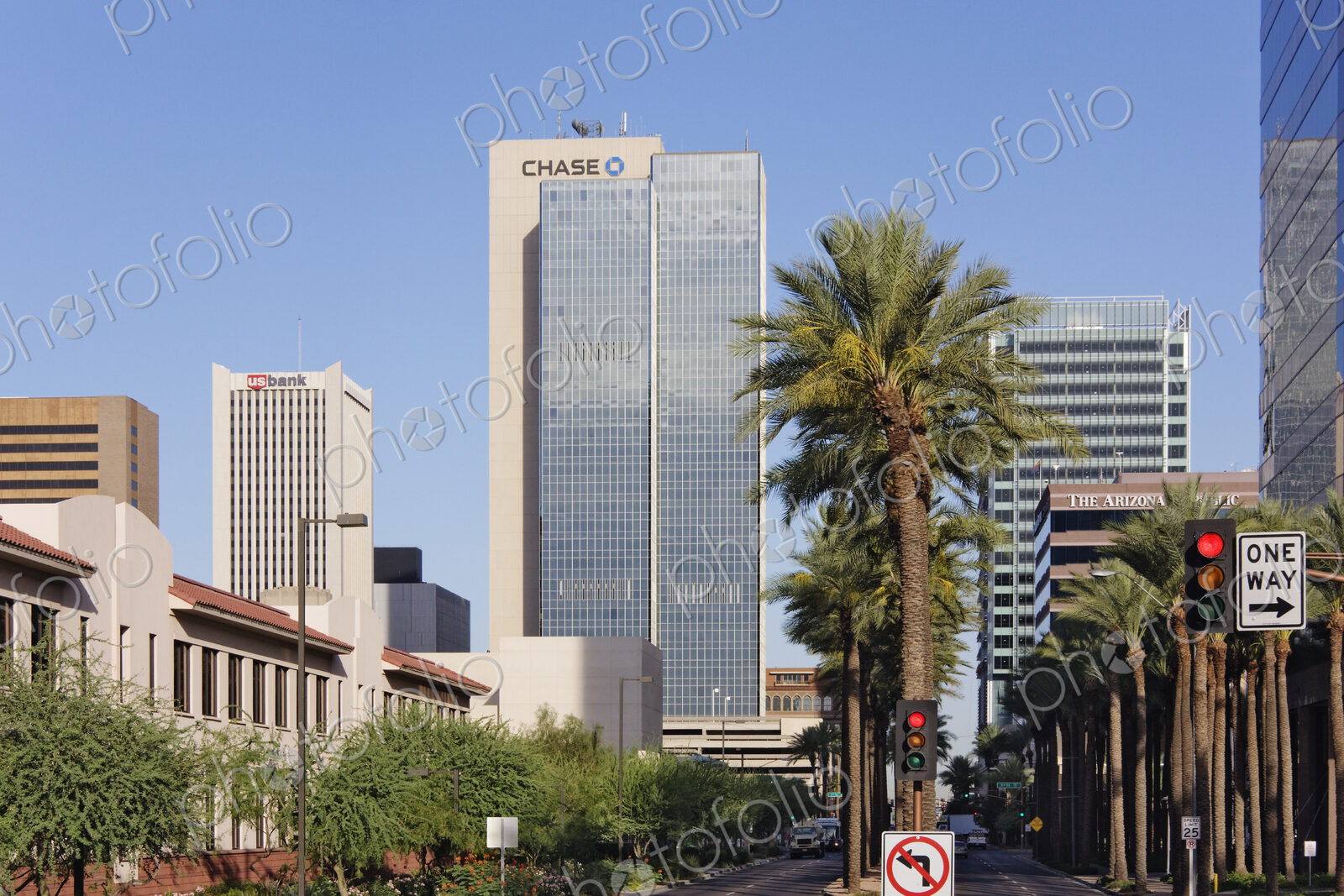 The buildings of downtown Phoenix, skyscrapers and palm trees, roads and stop lights.