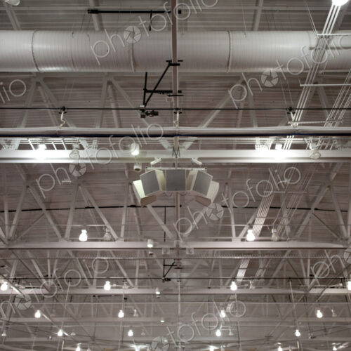 The ceiling of a large building, with air ducts and pipes, the rafters, gantry and…