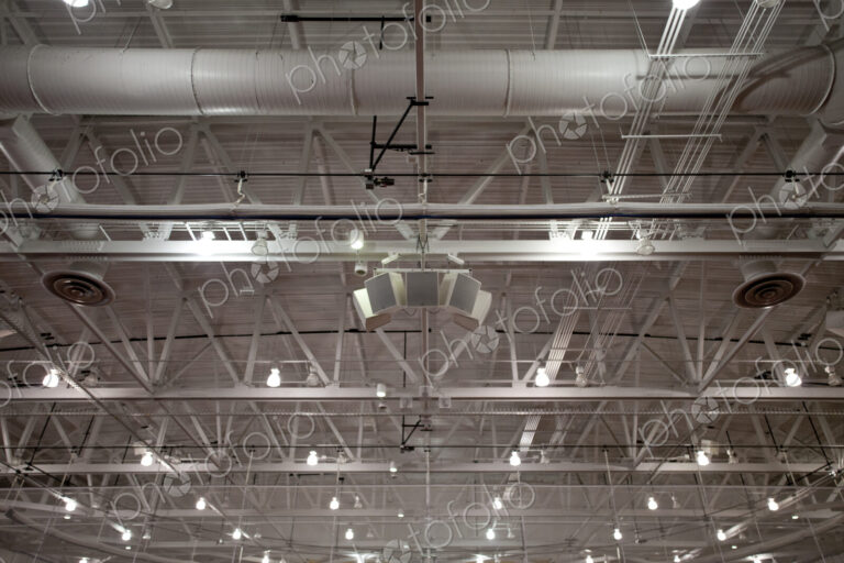 The ceiling of a large building, with air ducts and pipes, the rafters, gantry and…