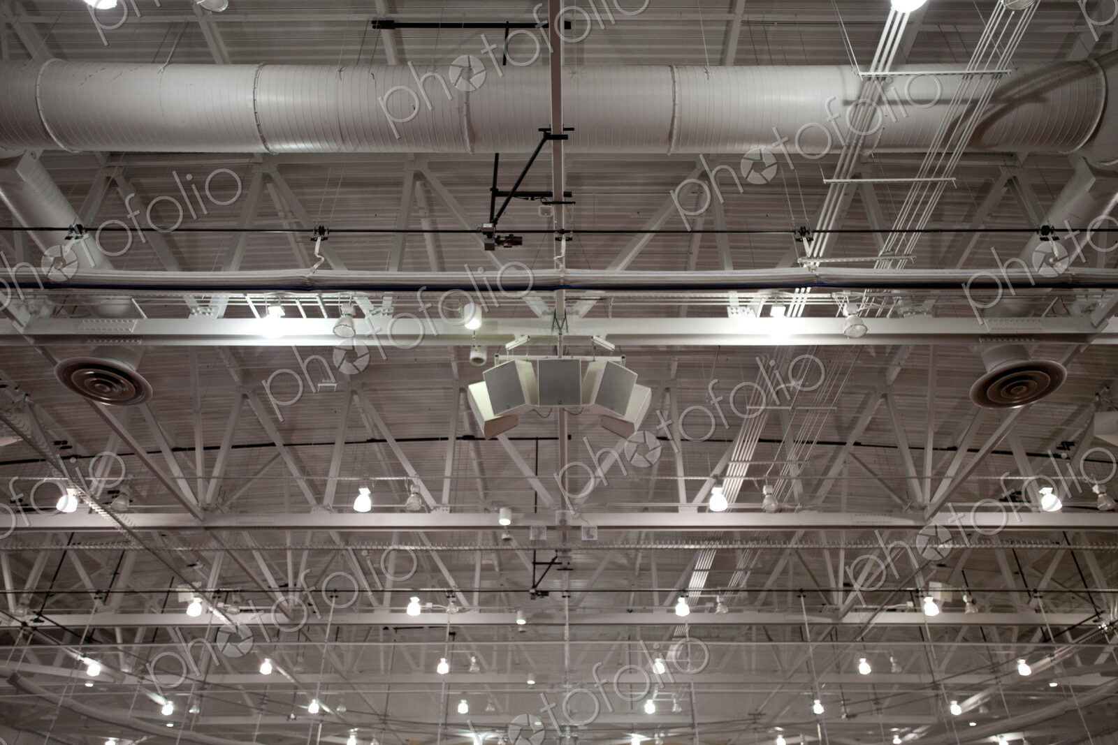 The ceiling of a large building, with air ducts and pipes, the rafters, gantry and…