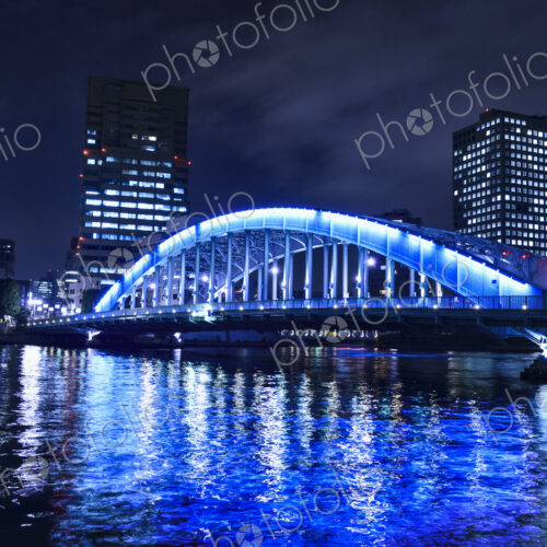 The city of Tokyo at night, the Sumida River and Eitai bridge, lit up, with high rise…