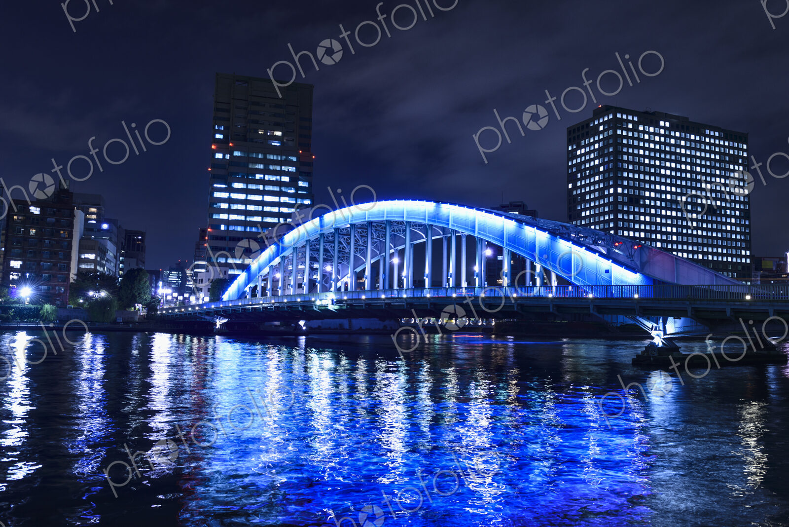 The city of Tokyo at night, the Sumida River and Eitai bridge, lit up, with high rise…