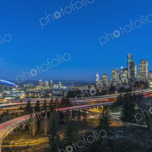 The city skyline of Seattle at night, road and bridge, downtown buildings lit up in…