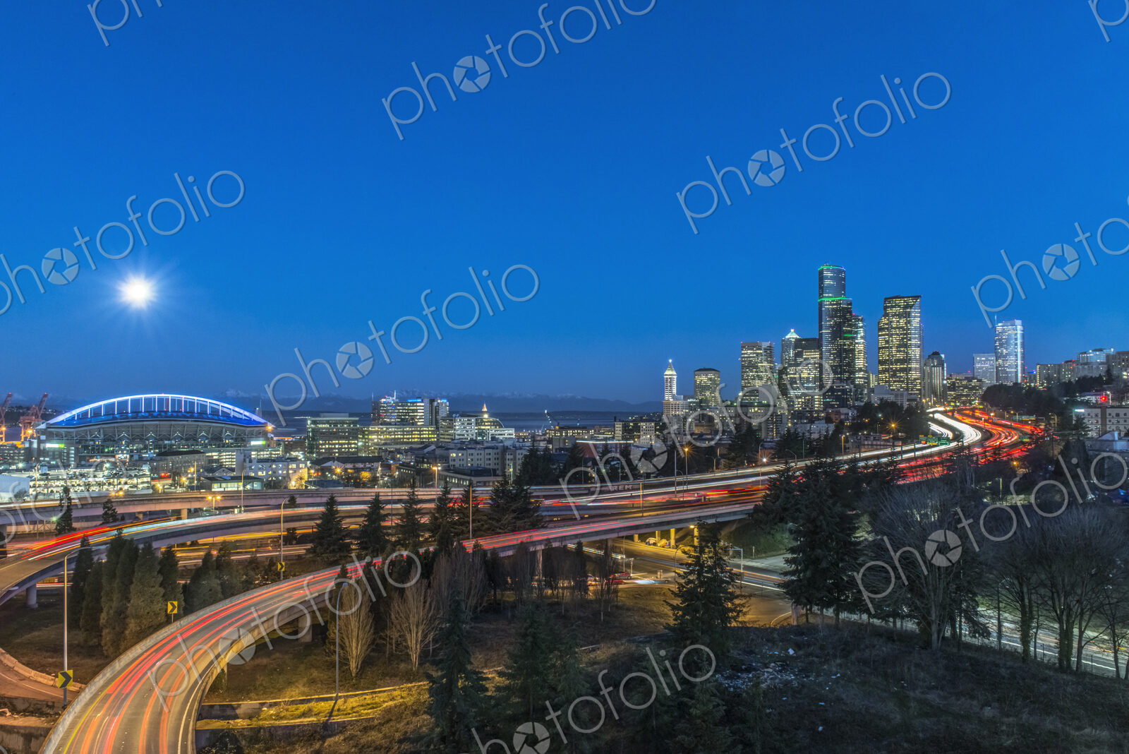 The city skyline of Seattle at night, road and bridge, downtown buildings lit up in…