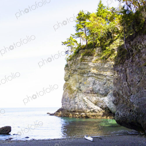 The cliffs at Freshwater Bay, a small kayak beached on shore.