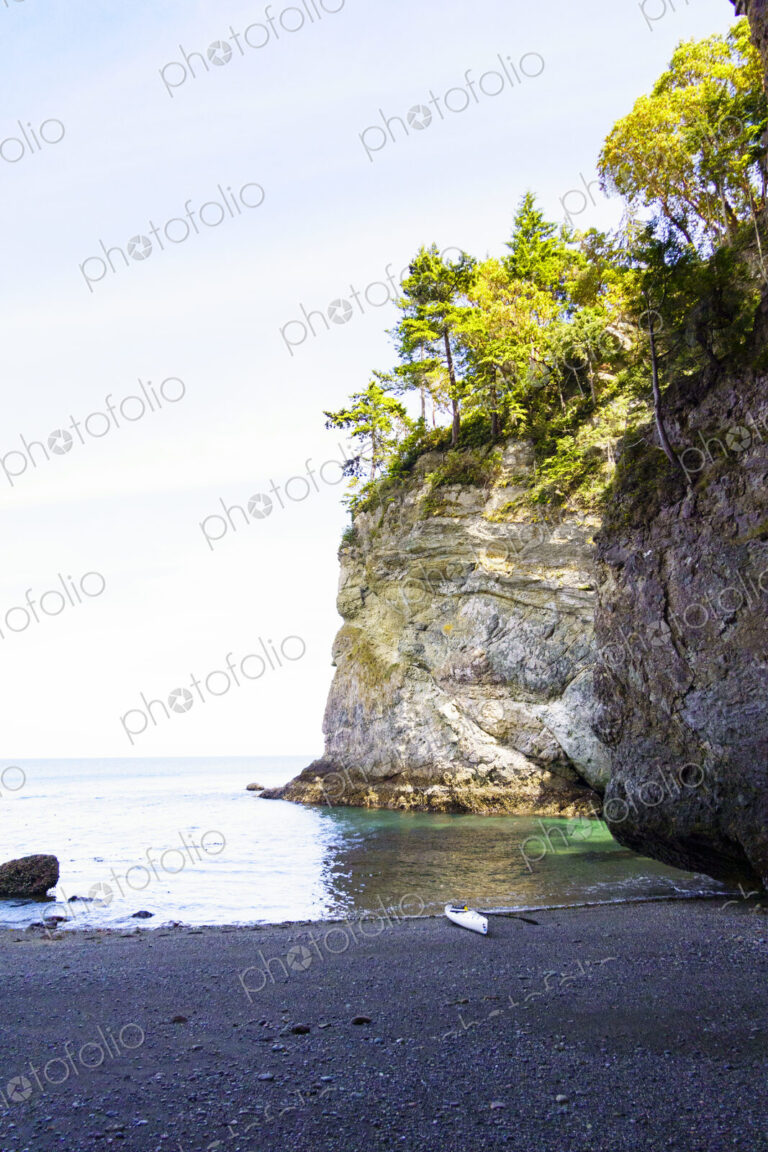 The cliffs at Freshwater Bay, a small kayak beached on shore.