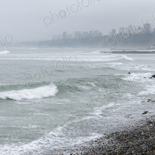 The coastline on a stormy day in Lima, white waves and view to the city.