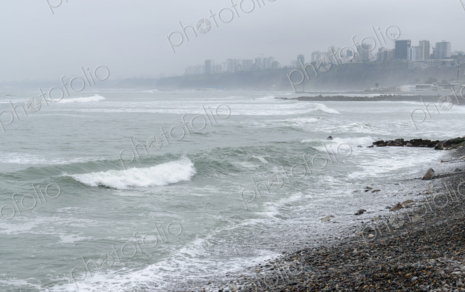 The coastline on a stormy day in Lima, white waves and view to the city.