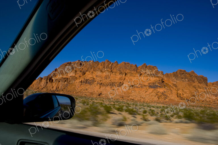 The driver's view of a side mirror, and the open window, a road trip through Red Rock…