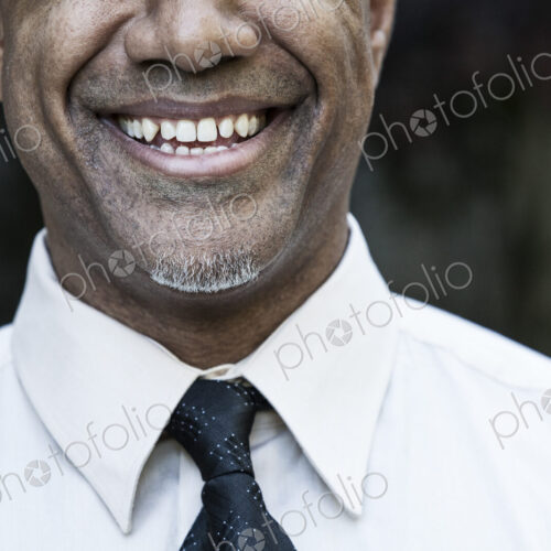 The face of a smiling businessman in a shirt and tie, nose and chin,