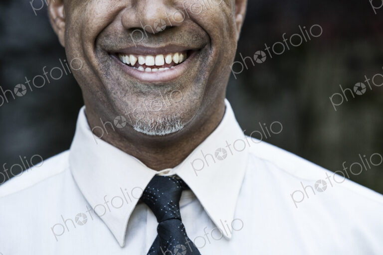 The face of a smiling businessman in a shirt and tie, nose and chin,