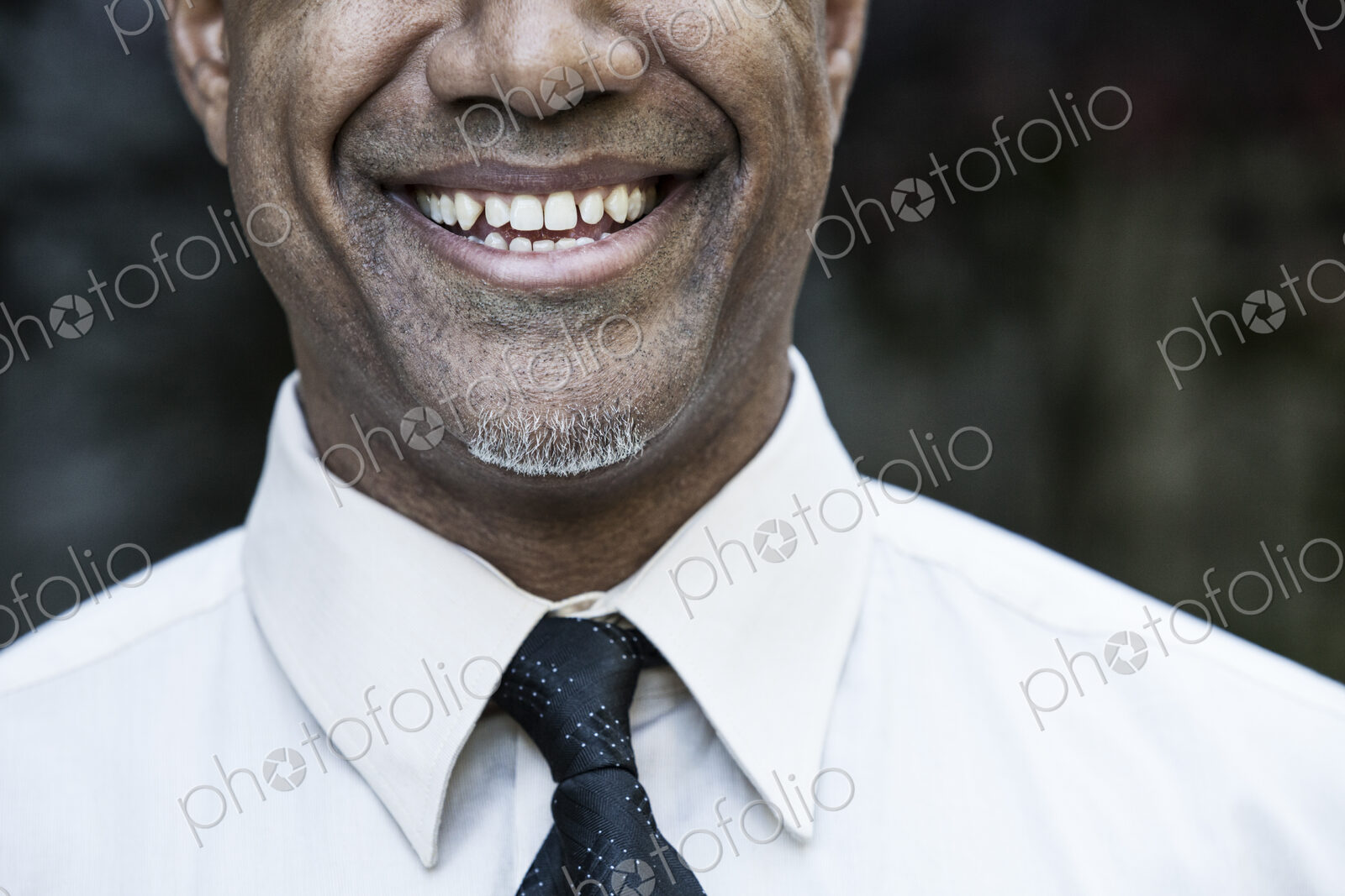 The face of a smiling businessman in a shirt and tie, nose and chin,