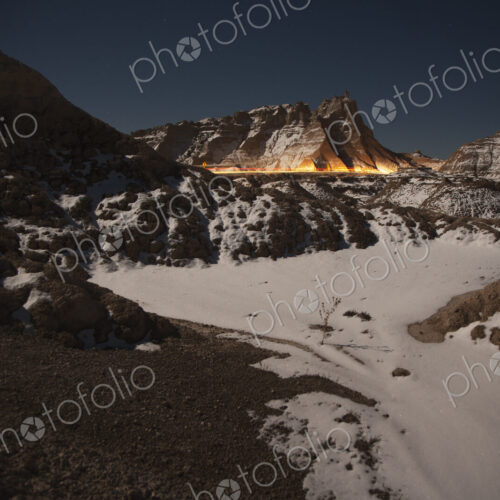 The glow of car headlights going through the Badlands National Park of South Dakota at… The glow of car headlights going through the Badlands National Park of South Dakota at…