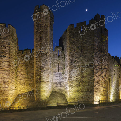The historic Norman motte and bailey Caernarfon Castle, walls lit up at dusk. The historic Norman motte and bailey Caernarfon Castle, walls lit up at dusk.