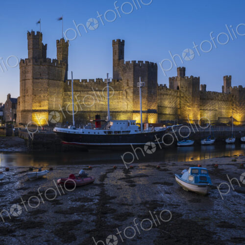 The historic Norman motte and bailey Caernarfon Castle, walls lit up at dusk, the… The historic Norman motte and bailey Caernarfon Castle, walls lit up at dusk, the…