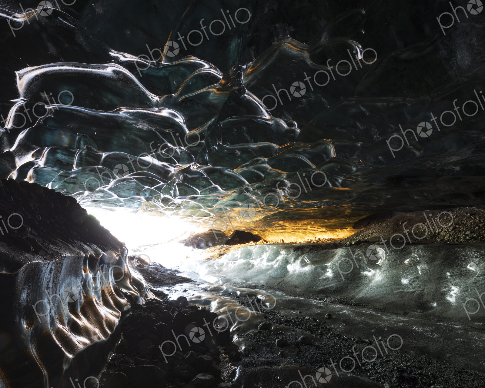 The interior of an ice cave with clear contoured ice on the ceiling, walls of ice and…