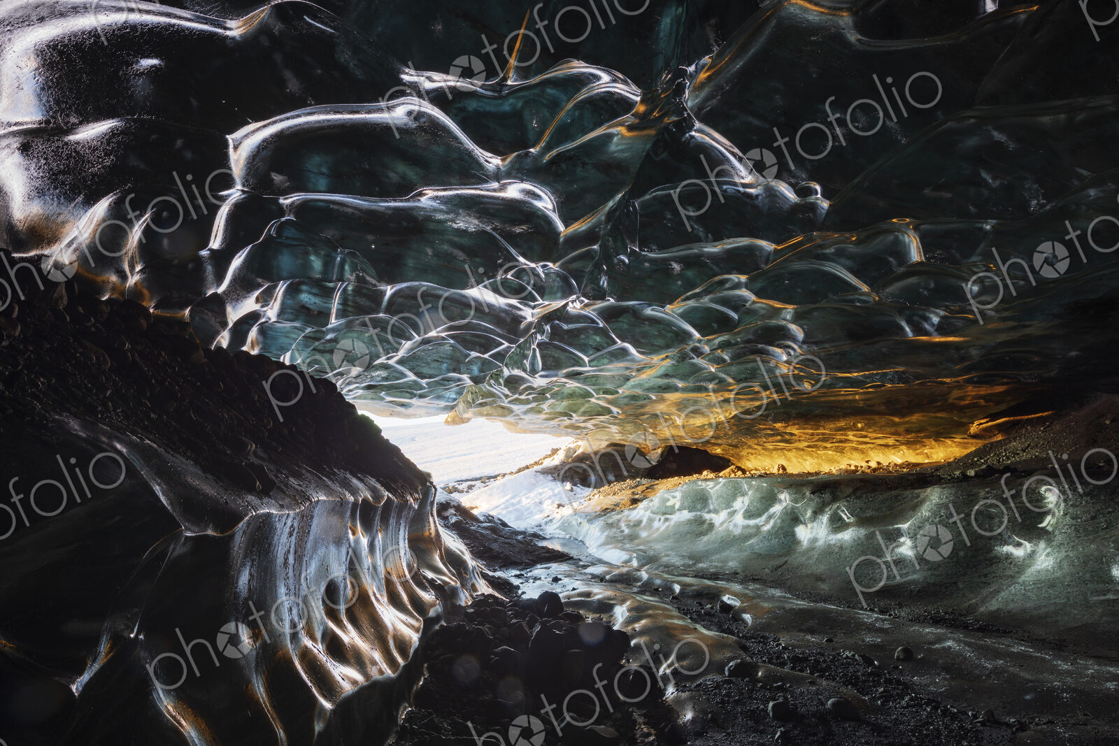 The interior of an ice cave with clear contoured ice on the ceiling, walls of ice and…