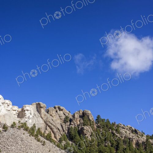 The presidential carvings of Mount Rushmore sit beneath a deep blue sky as a lone…