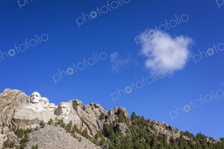 The presidential carvings of Mount Rushmore sit beneath a deep blue sky as a lone…
